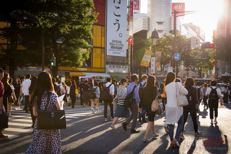 various Japanese people crossing the Shibuya crossing in sunlight