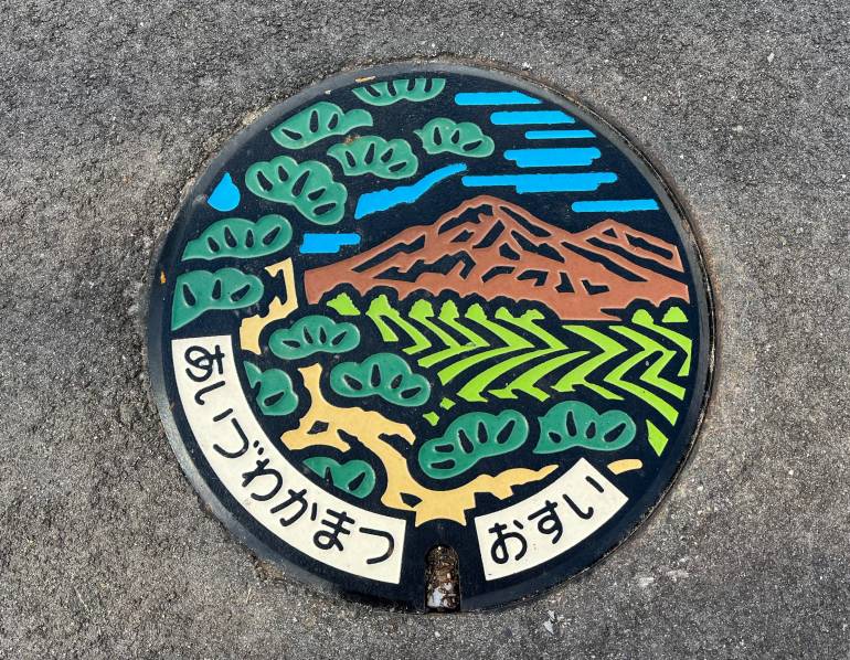 Manhole cover with 'Aizu-Wakamatsu' in Japanese and landscape design 