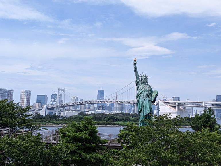 A daytime view of the Statue of Liberty and Rainbow Bridge from Odaiba